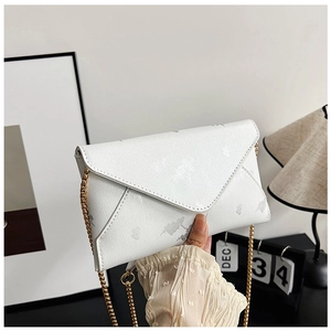Detail of white envelope chain bag featuring a floral print and golden chain strap