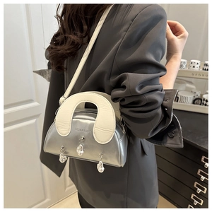 Detail of silver metallic shell bag featuring irregular pearl pendants and thin strap