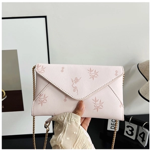 Close-up of pink envelope crossbody bag featuring floral print and gold chain strap
