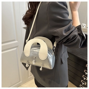 Silver metallic shell bag with ivory straps and liquid metal charms on a business suit