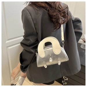 Detail of silver metallic shell bag with pearl charms and white U-shaped handle