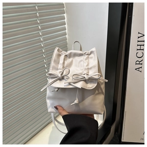 Détail du sac à dos blanc cassé avec nœud, fermeture à cordon et texture en cuir