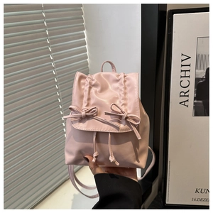 Vue détaillée d'un mini sac à dos en cuir rose avec nœud élégant et fermeture à cordon
