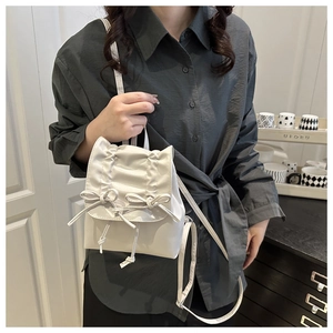 Detail of cream white pleated backpack with decorative bows and glossy PU leather finish