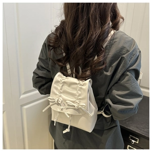 Détail du mini sac à dos blanc plissé avec des nœuds élégants en cuir PU souple
