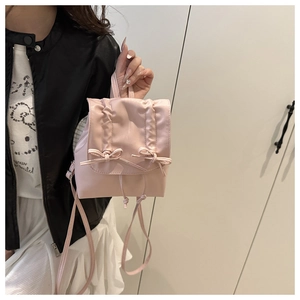 Detailed close-up of pink pleated mini backpack with ribbon bow and drawstring