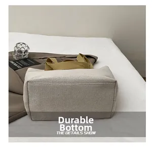 Detail of the reinforced wear-resistant base and khaki strap on a canvas tote bag