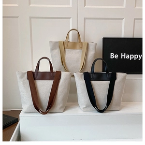 Detailed view of canvas tote bags in beige, brown and black with leather handles