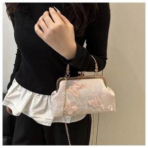 Detailed close-up of pink butterfly embroidery and gold clasp on a vintage handbag
