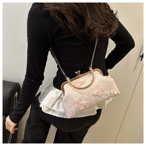 Detail of cream lace crossbody bag featuring 3D butterfly embroidery and gold chain strap
