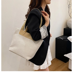 Minimalist canvas tote bag with brown leather trim shown on shoulder in a modern room