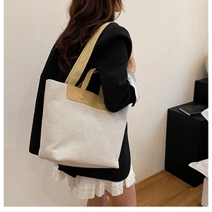 Detail view of large canvas tote bag with brown leather handles and dual shoulder straps