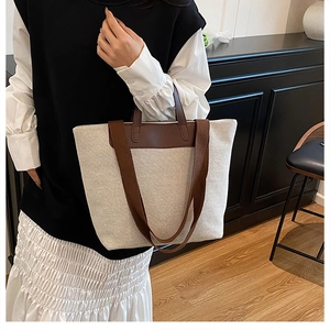 Detail showing beige canvas tote bag with contrast brown leather handles and shoulder strap