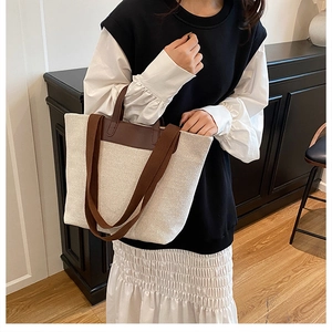 Detailansicht einer großen Canvas-Einkaufstasche mit braunen Ledergriffen am Model