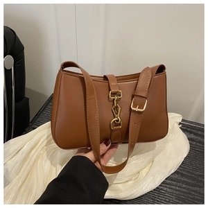 Gros plan d'un sac demi-lune en cuir marron avec boucle piston dorée et bandoulière