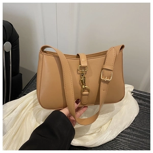 Détail d'un sac sous le bras en cuir mat camel avec un fermoir piston doré signature