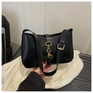 Détail du sac hobo noir avec fermoir à piston doré vintage sur fond de soie