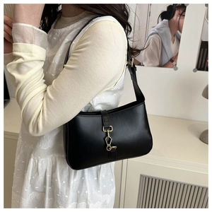 Détail du sac sous le bras noir avec boucle en métal doré et bandoulière réglable