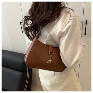 Model wearing a vintage brown leather crescent bag with gold piston clasp detail