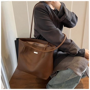Dettaglio della borsa tote in pelle marrone con grana litchi e inserto in metallo argento