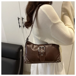 Modella che indossa borsa tote in pelle marrone scuro con borchie e fibbia in metallo
