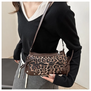 Dettaglio borsa baguette leopardata con bordi in pelle marrone e fiocchi decorativi
