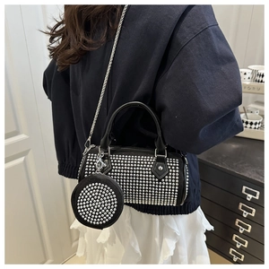 Detail of black cylinder bag with silver studs, chain strap and small round pouch
