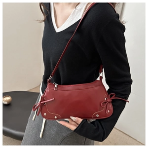 Dettaglio della borsa a mezzaluna in pelle bordeaux con fiocchi e rivetti argentati