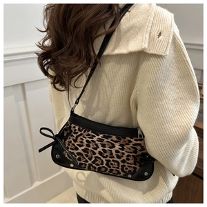 Close-up of leopard print underarm bag with black bow detail and silver studs on strap