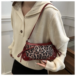 Dettaglio della borsa sottobraccio leopardata con finiture in pelle rossa e tracolla