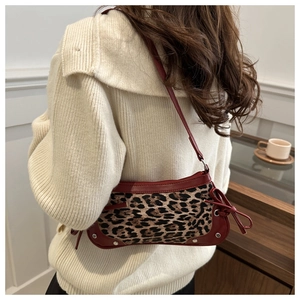 Dettaglio borsa a mezzaluna leopardata con finiture in pelle bordeaux e fiocco