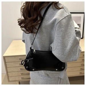 Dettaglio borsa hobo in pelle nera con borchie argentate e fiocco laterale su modella