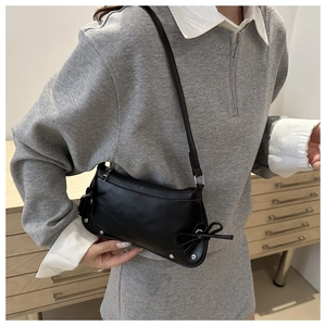 Dettaglio della borsa a mezzaluna nera con borchie argento e fiocco decorativo in pelle