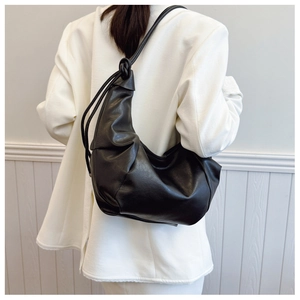 Detail of black dumpling hobo bag featuring soft pleated texture and stylish knot strap