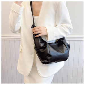 Detail of minimalist black dumpling bag with soft pleated texture and stylish knot strap