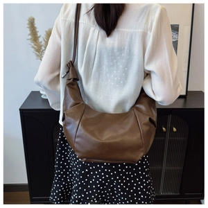 Detail shot of a large brown hobo bag showing pleats and knotted strap on model
