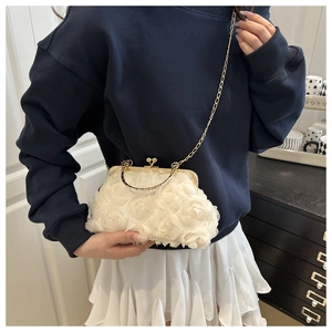 Detailed view of 3D white fabric rose flowers and golden metal clasp on the shell bag