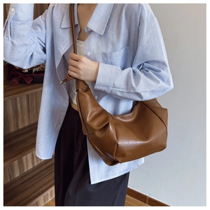 Close-up of brown faux leather half-moon shoulder bag with unique knot detail on strap