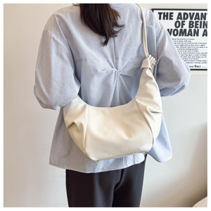Detailed view of the knotted shoulder strap and leather texture on a white crescent bag