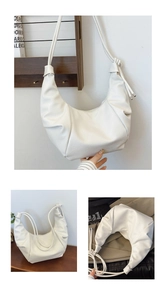 Detail of warm white soft leather dumpling bag with knotted strap and silver pendant