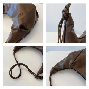 Detail view of brown pleated shoulder bag showing stitching, zipper, and large knot handle