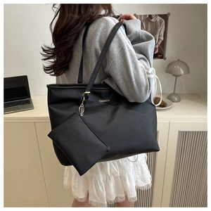 Detail view of a large black faux leather tote bag with FASHION logo and small pouch