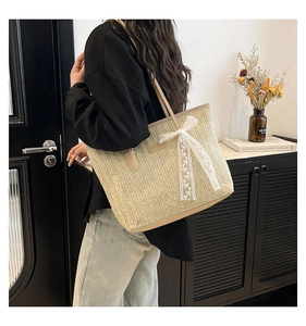 Détail du sac cabas en paille avec nœud en dentelle blanche et bandoulière en cuir