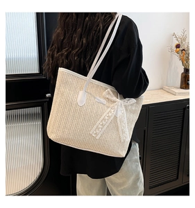 Détail du sac cabas en paille tissée avec bordure en cuir blanc et nœud en dentelle élégant