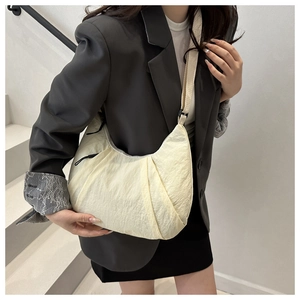 Détail du sac demi-lune crème minimaliste avec tissu plissé texturé et bandoulière réglable