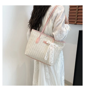 Detail of summer straw tote bag with pink leather trim and white lace ribbon bow