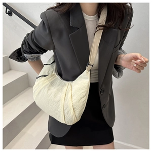 Vue latérale du sac croissant plissé crème avec bandoulière sur un mannequin