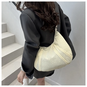 Sac fourre-tout beige plissé porté par un mannequin dans un cadre très minimaliste