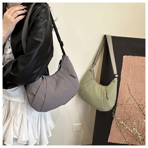 Détail du sac demi-lune en nylon souple avec design plissé et bandoulière réglable
