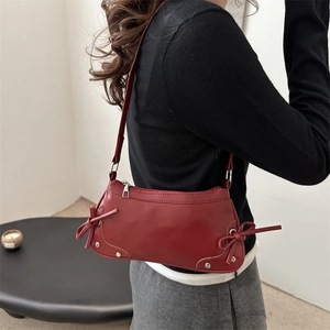 Borsa a spalla rossa a mezzaluna con fiocchi e borchie indossata da una modella